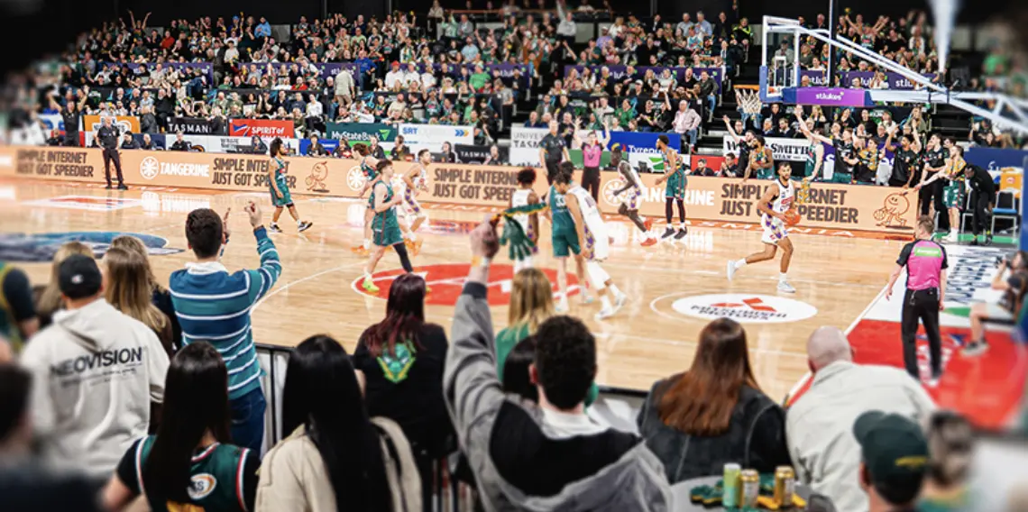 Fans courtside with drinks on the table as the JackJumpers play at MyState Bank Arena